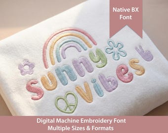 May include: A white fabric featuring an embroidered design with a pastel rainbow, a flower, a heart, and a peace sign. The text reads "sunny vibes" in multi-coloured, stitched lettering. A tag in the corner displays "Native BX Font".