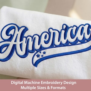 Puede incluir: Tela blanca con la palabra "America" bordada en azul. El diseño incluye un contorno azul y una pancarta azul con tres estrellas. El texto "Digital Machine Embroidery Design Multiple Sizes & Formats" se muestra en la parte inferior.