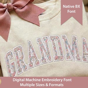 Könnte beinhalten: Ein cremefarbenes Sweatshirt mit dem Wort GRANDMA in großen Blockbuchstaben, die mit einem rosa-blauen Blumenmuster gefüllt sind. Eine große, altrosa Schleife ist an der oberen linken Ecke befestigt. Der Text auf dem Bild lautet Native BX Font und Hand Digitized Digital Machine Embroidery Font Multiple Sizes & Formats.