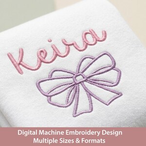 May include: White fabric with embroidered design. The design includes the name "Keira" in pink script above a lavender bow. The text "Digital Machine Embroidery Design Multiple Sizes & Formats" is at the bottom.