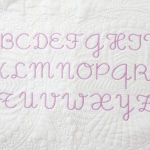 Peut inclure: Un tissu blanc avec un alphabet brod&eacute; en rose, comprenant toutes les lettres de A &agrave; Z.