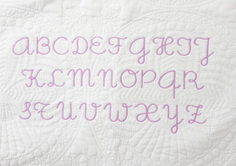 Peut inclure: Un tissu blanc avec un alphabet brod&eacute; en rose, comprenant toutes les lettres de A &agrave; Z.