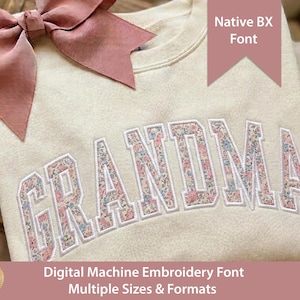 Könnte beinhalten: Ein cremefarbenes Sweatshirt mit dem Wort GRANDMA, das in einem Blumenmuster mit rosa, blauen und grünen Blüten gestickt ist. Eine große altrosa Schleife ist an der oberen linken Ecke befestigt. Der Text auf dem Bild lautet Native BX Font und Digital Machine Embroidery Font Multiple Sizes & Formats.