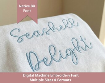 May include: A white fabric surface featuring light blue machine embroidery in a cursive script font that reads Seashell Delight. A pink banner at the top displays the text Native BX Font, and a pink bar at the bottom reads Digital Machine Embroidery Font Multiple Sizes & Formats.