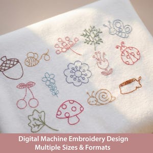 May include: White fabric with embroidered designs of an acorn, bee, cherries, flower, leaf, mushroom, snail, butterfly, ladybug, and other floral elements. The text at the bottom reads "Digital Machine Embroidery Design Multiple Sizes & Formats."