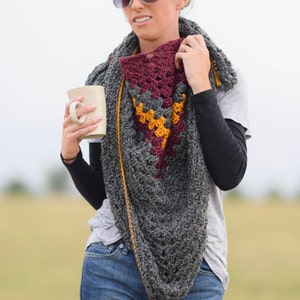 Puede incluir: Una mujer con un chal de ganchillo gris, burdeos y amarillo con una taza blanca en la mano.