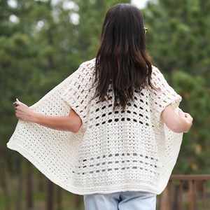 May include: A white crochet cardigan with a lacy openwork design. The cardigan has a relaxed fit and short sleeves.