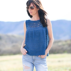 Pu&ograve; includere: Una donna indossa un top blu senza maniche all'uncinetto con un collo di pizzo e jeans di denim consumati.
