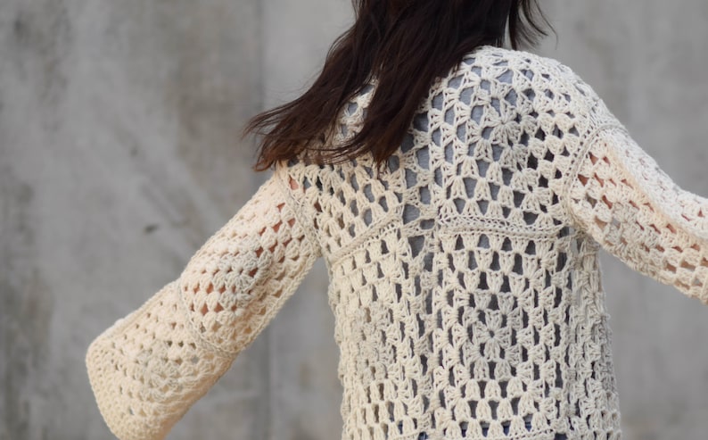 May include: A white crocheted cardigan with a lacy pattern. The cardigan has long sleeves and a loose fit.