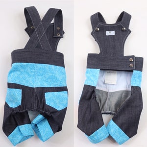May include: Blue and black denim overalls with a floral pattern on the legs. The overalls have adjustable straps and a snap closure.