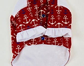 May include: Red dog shirt with white anchor print and white ruffle trim. The shirt has blue buttons.