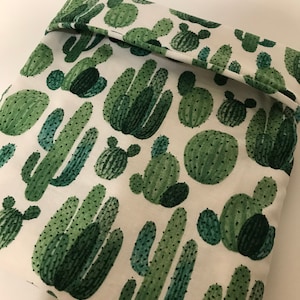 Puede incluir: Tela blanca con un patrón repetido de plantas de cactus verdes. Las plantas de cactus son de varios tamaños y formas.