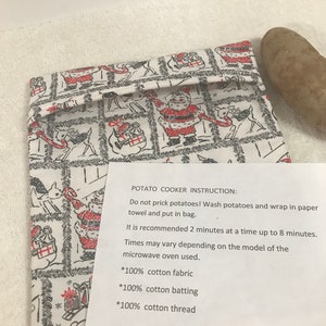 Puede incluir: Una bolsa de algodón blanca con un estampado de Papá Noel. La bolsa es para cocinar patatas en el microondas. Las instrucciones en la tarjeta dicen que se laven las patatas, se envuelvan en una toalla de papel y se pongan en la bolsa. Se recomienda cocinar las patatas durante 2 minutos a la vez, hasta 8 minutos. La bolsa está hecha de 100% algodón, guata e hilo.