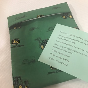 May include: Green fabric potato cooker bag with a John Deere logo and tractor print. The bag is made with 100% cotton fabric, batting, and thread. Instructions on the bag read: "POTATO COOKER INSTRUCTION Do not prick potatoes! Wash potatoes! Towel and put in bag. It is recommended 2 minutes at a time. Times may vary depending on the microwave oven used."