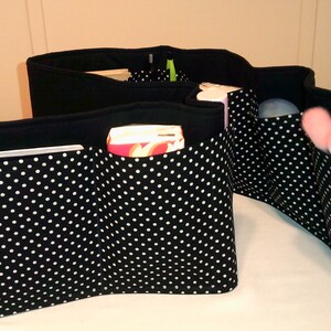 May include: Black and white polka dot fabric organizer with multiple pockets for a purse or handbag. The organizer has a zipper closure and is filled with various items, including a book, a box of tissues, and a makeup brush.