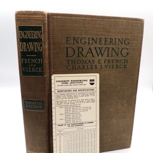 May include: A brown hardcover textbook titled Engineering Drawing by Thomas E. French and Charles J. Vierck, Eighth Edition, standing next to a rectangular beige Concrete Reinforcing Steel Institute reference card with printed technical specifications.