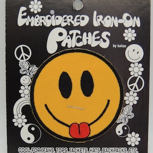 May include: Yellow embroidered iron-on patch of a smiley face with a red tongue sticking out. The patch is on a black card with white text that reads "Embroidered Iron-On Patches by Kalan" and "Cool for jeans, tops, jackets, hats, backpacks, etc."