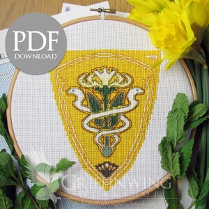 May include: A cross-stitch project in a wooden hoop features a yellow and green emblem with a serpent and floral design. The text "PDF DOWNLOAD" is visible. Fresh daffodils and mint sprigs surround the embroidery, suggesting a craft or home decor theme.