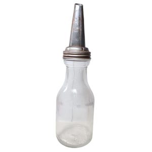 May include: A clear glass bottle with a narrow neck and a wide base, topped with a metallic, conical pouring spout. The glass features embossed text that reads ONE LIQUID QUART, indicating its capacity, with a threaded metal collar.
