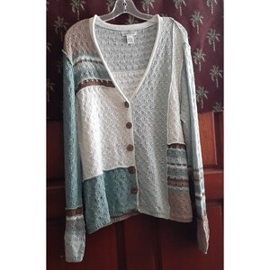 May include: A white, blue, and brown knitted cardigan with a button closure. The cardigan has a v-neck and long sleeves.