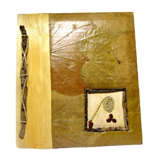 May include: A handmade journal with a brown wood cover and a decorative design of dried leaves. The cover has a small window with a woven design and red beads.