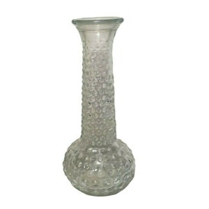 May include: A clear glass vase with a textured, bubble-like design. The vase has a round base and a tall, slender neck.