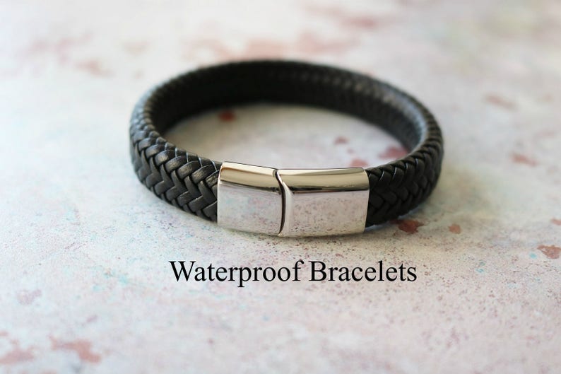 Op de afbeelding: Een zwarte leren armband met een zilveren sluiting. De armband is gevlochten en heeft een eenvoudig ontwerp. Waterdichte armbanden.