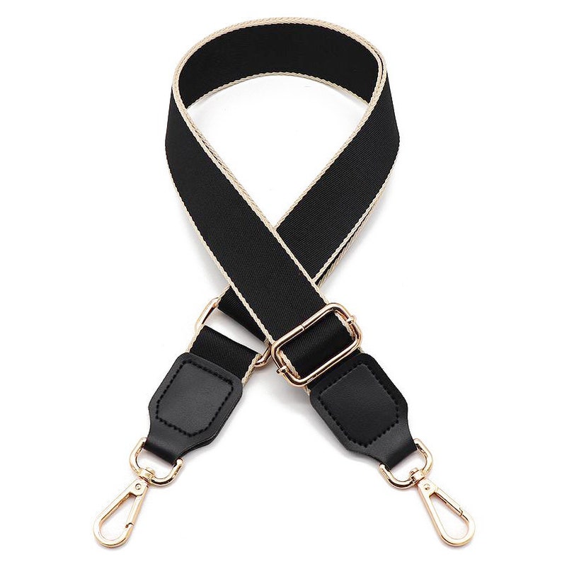 May include: A black adjustable bag strap featuring a woven texture with beige edges. The strap includes gold-toned metal hardware, including a sliding buckle and two swivel lobster clasps attached to black faux leather tabs at each end.