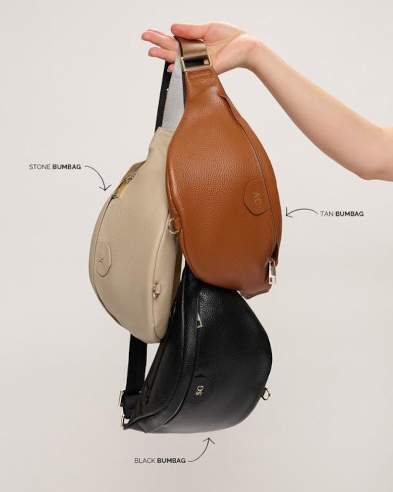 Peut inclure: Trois sacs banane en couleurs pierre, fauve et noir, chacun pr&eacute;sentant une finition textur&eacute;e, une fermeture &eacute;clair et une sangle r&eacute;glable. Les sacs sont &eacute;tiquet&eacute;s STONE BUMBAG, TAN BUMBAG et BLACK BUMBAG avec des fl&egrave;ches les d&eacute;signant.