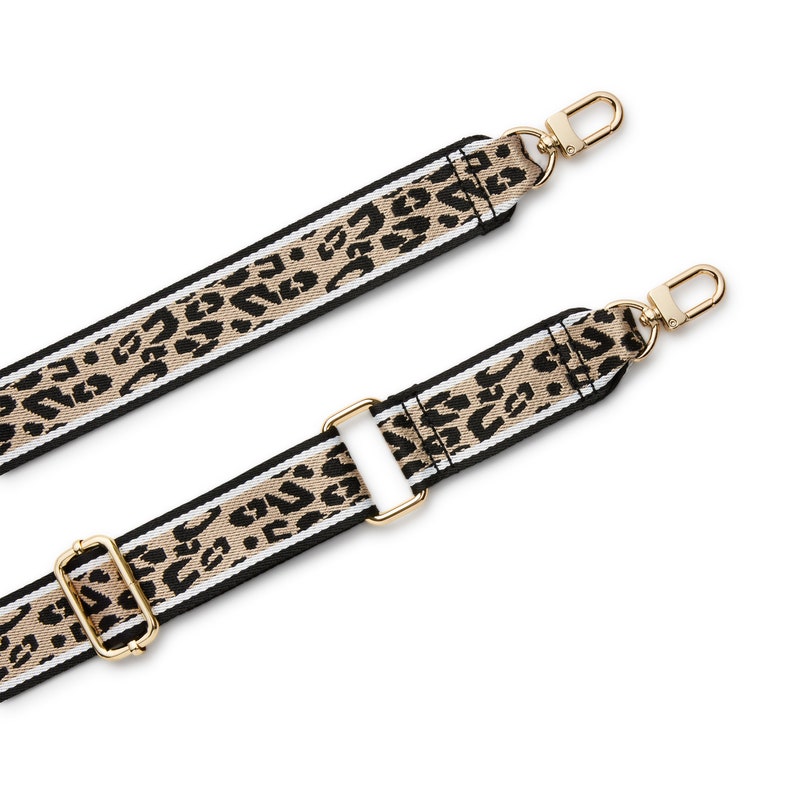 May include: A replacement bag strap featuring a tan and black leopard print pattern with white side stripes. The strap includes gold-toned metal hardware, including two swivel lobster clasps at the ends and two adjustable sliders for length modification.