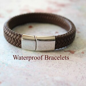 Op de afbeelding: Een bruin leren armband met een zilveren sluiting. De armband is gevlochten en heeft een eenvoudig ontwerp. Waterdichte armbanden.
