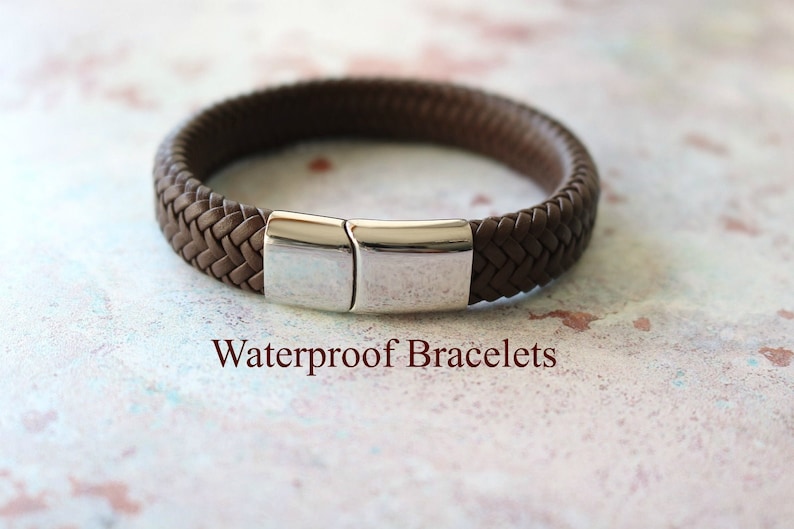 Op de afbeelding: Een bruin leren armband met een zilveren sluiting. De armband is gevlochten en heeft een eenvoudig ontwerp. Waterdichte armbanden.