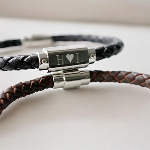 May include: Two braided leather bracelets with a silver clasp engraved with the initials "H" and "L" separated by a heart symbol.