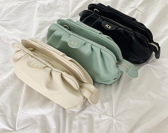 May include: Three small,  pleated,  handbags in white, light green, and black with gold hardware and the initials "K.S." on the front.