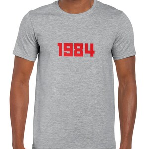 May include: A heather grey t-shirt with the number 1984 printed in red on the front.