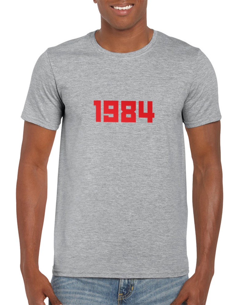 May include: A heather grey t-shirt with the number 1984 printed in red on the front.