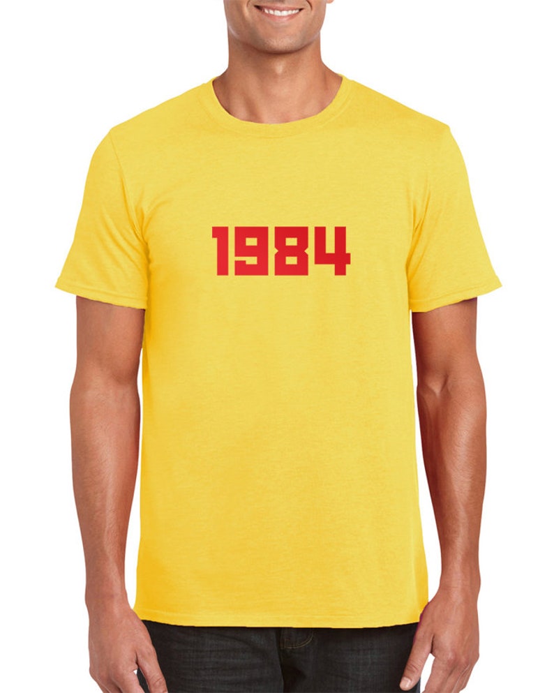 May include: Yellow short-sleeved t-shirt with the number 1984 printed in red on the front.