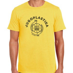 Könnte beinhalten: Ein gelbes T-Shirt mit einem schwarzen Basketball-Logo. Das Logo zeigt zwei Hände, die einen Basketball halten, mit dem Text "JUGOPLASTIKA" außen herum und "basketball club split" unter dem Basketball.