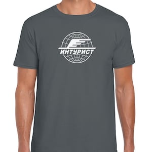 Puede incluir: Una camiseta gris oscuro con un logotipo blanco de un globo terráqueo con un avión estilizado y el texto "ИНТУРИСТ" en escritura cirílica.