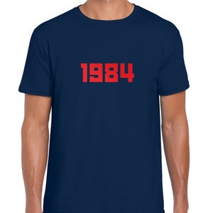 May include: A navy blue t-shirt with the number 1984 printed in red on the front.