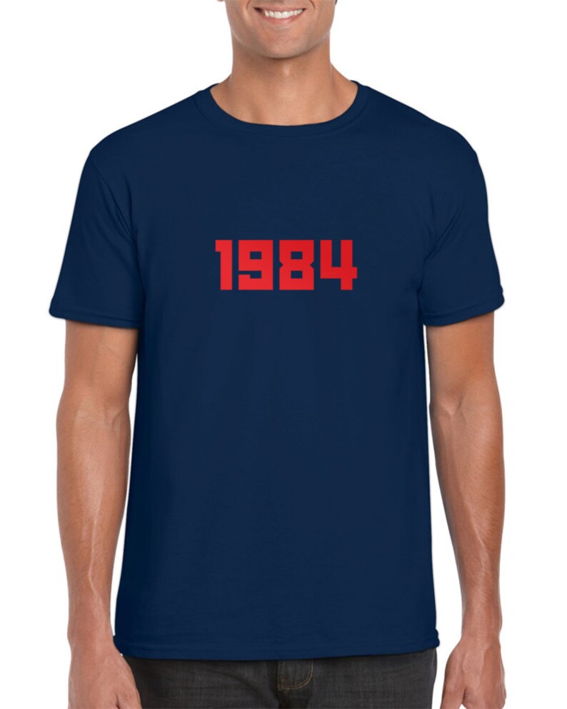 May include: A navy blue t-shirt with the number 1984 printed in red on the front.