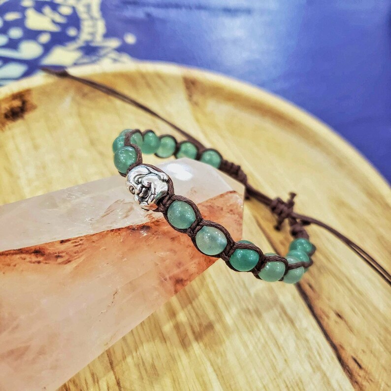 Peut inclure: Un bracelet en jade vert avec un charme en argent. Le bracelet est fait avec un cordon brun et a un n&oelig;ud &agrave; l'extr&eacute;mit&eacute;.