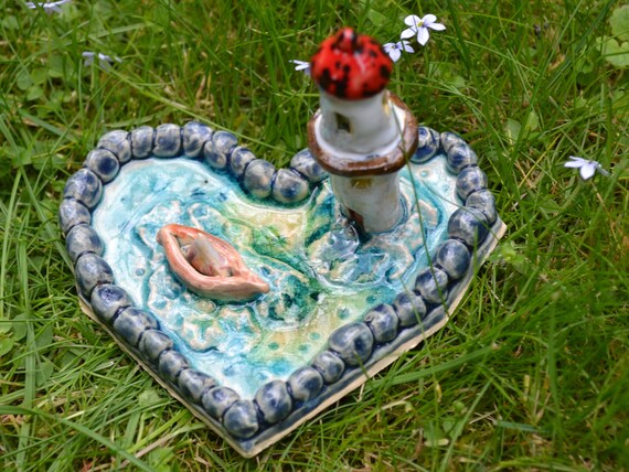 Mini ceramic heart boat in the sea with lighthouse