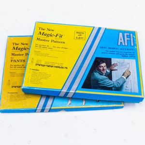 Puede incluir: Dos cajas azules y amarillas con el texto "The New Magic-Fit Master Pattern" y "The New Magic-Fit Master Pattern for PANTS". Las cajas están apiladas una encima de la otra. La caja superior tiene una imagen de un hombre con traje sosteniendo una hoja de papel con un patrón en ella. El texto "AFI NEW! SIMPLE! ACCURATE!" está en la caja. El texto "Designing with Sudan" está en la caja superior.