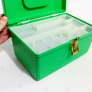 Puede incluir: Una caja de almacenamiento de pl&aacute;stico verde con un cierre y compartimentos en el interior. La caja est&aacute; abierta y la tapa est&aacute; levantada.