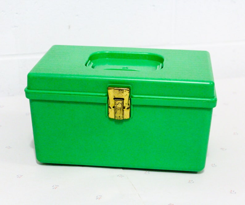 Puede incluir: Una caja de almacenamiento de pl&aacute;stico verde brillante con un cierre dorado. La caja tiene una tapa con bisagras y es ideal para organizar art&iacute;culos peque&ntilde;os.