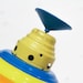 May include: A vintage rainbow-colored metal spinning top with a blue plastic spinning top on top.