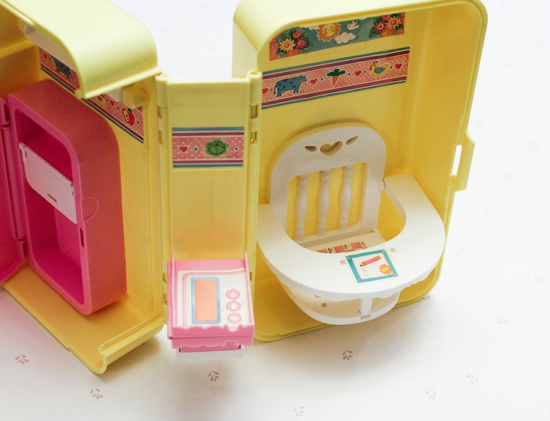 May include: A yellow plastic toy playhouse with a pink refrigerator, a white high chair, and a pink stove. The playhouse has a floral pattern on the outside.