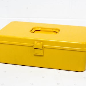 May include: A bright yellow plastic storage box with a hinged lid and a carrying handle. The box has a latch on the front.