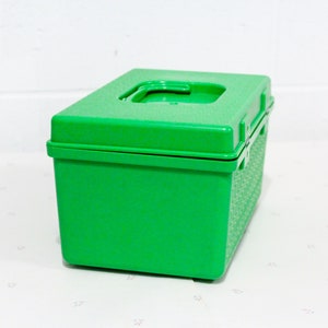 Puede incluir: Una caja de almacenamiento de pl&aacute;stico verde brillante con una tapa con bisagras. La caja tiene una superficie texturizada y una peque&ntilde;a manija en la tapa.